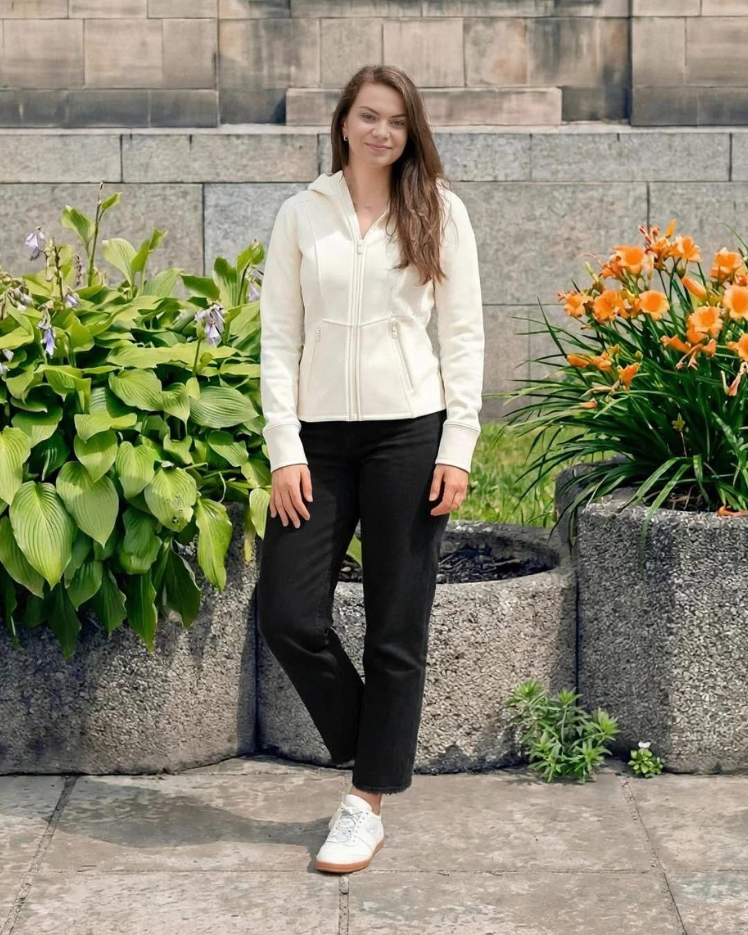 A cream zip jacket with black straight-leg jeans and white sneakers