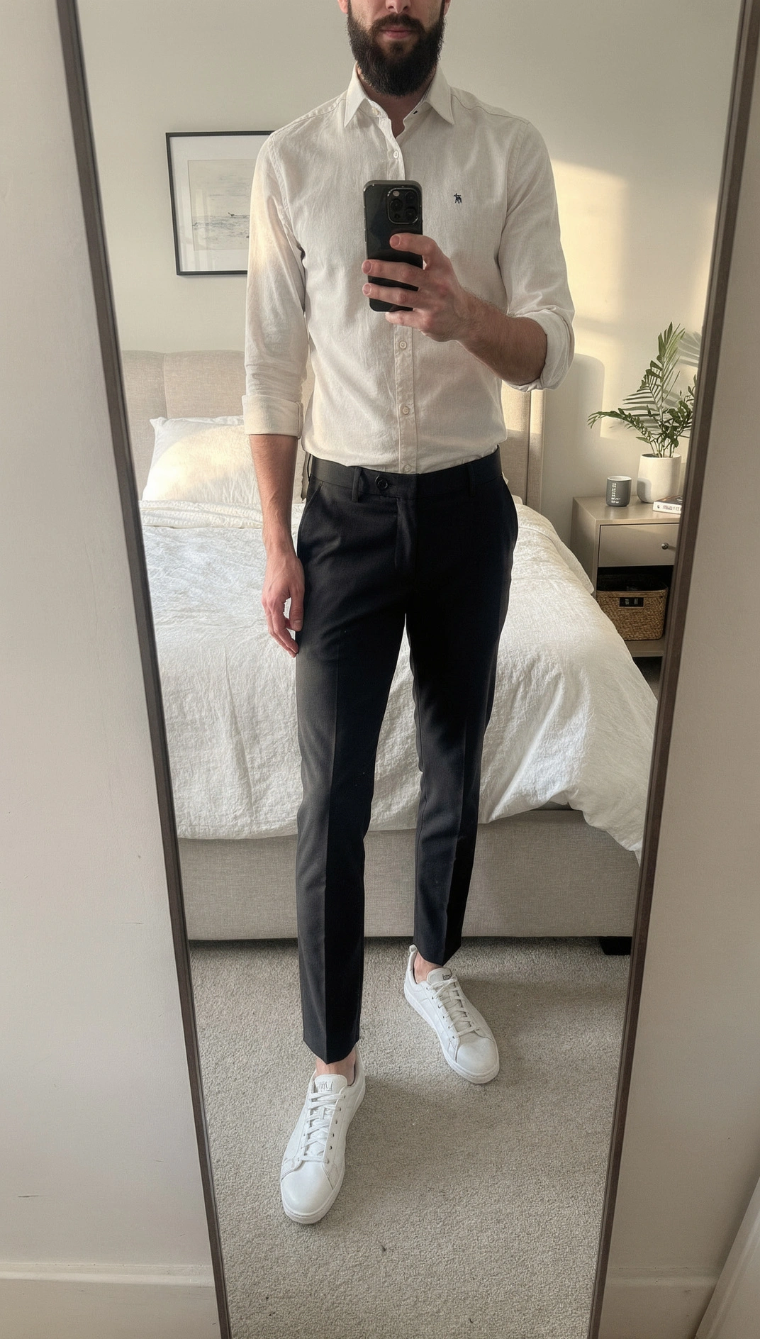 A man's full-length mirror selfie in a white shirt with rolled sleeves, charcoal slim trousers and white leather sneakers